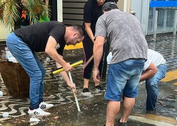 Lojistas desentopem bueiros durante alagamento em Poços de Caldas