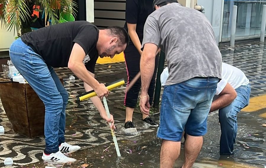 Lojistas desentopem bueiros durante alagamento em Poços de Caldas