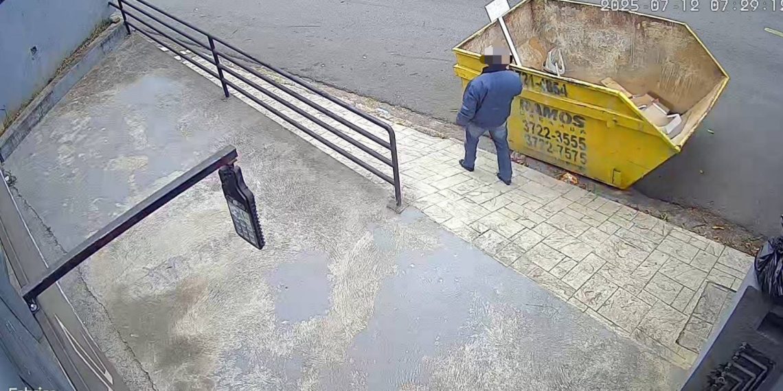 Homem retira placa de aviso e descarta entulho em caçamba alugada por empresa
